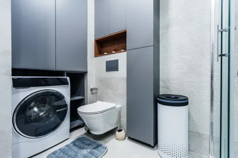 Modern bathroom with a washing machine, built-in cabinets and a wall-mounted toilet. - image 11