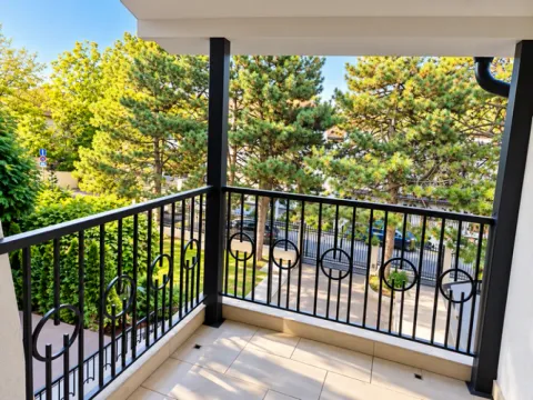 Covered balcony with a black metal railing and a view of greenery. - image 22