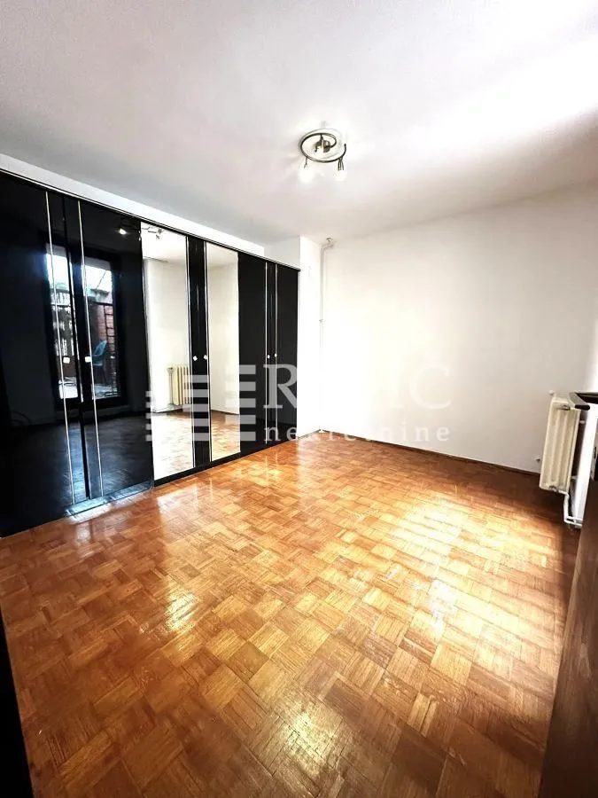 Empty room with parquet flooring and a large built-in wardrobe with a mirror.