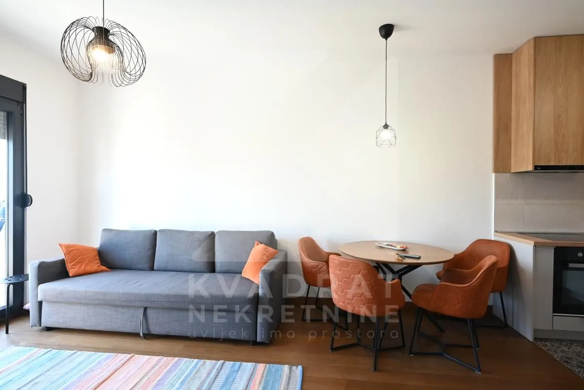 Living room with a sofa and dining table, connected to the kitchen.