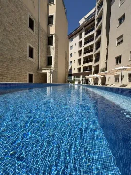 Outdoor swimming pool located between residential buildings with sun loungers and umbrellas. - image 11