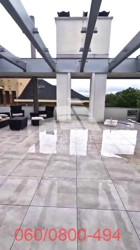 Velika popločana terasa sa pergolom i garniturom za sedenje.