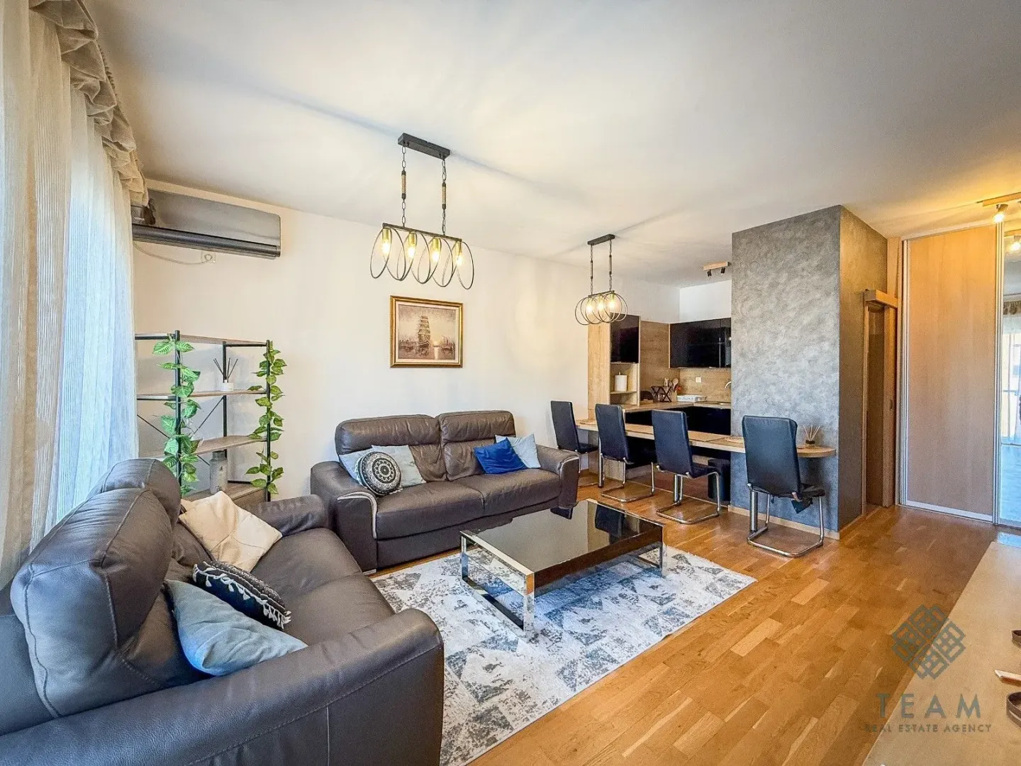 Living room with a sofa, coffee table, and dining area in the background.