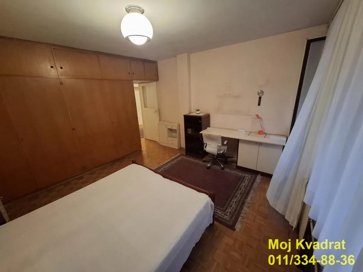 Nameštena spavaća soba sa krevetom, ugradnim plakarom i radnim stolom.