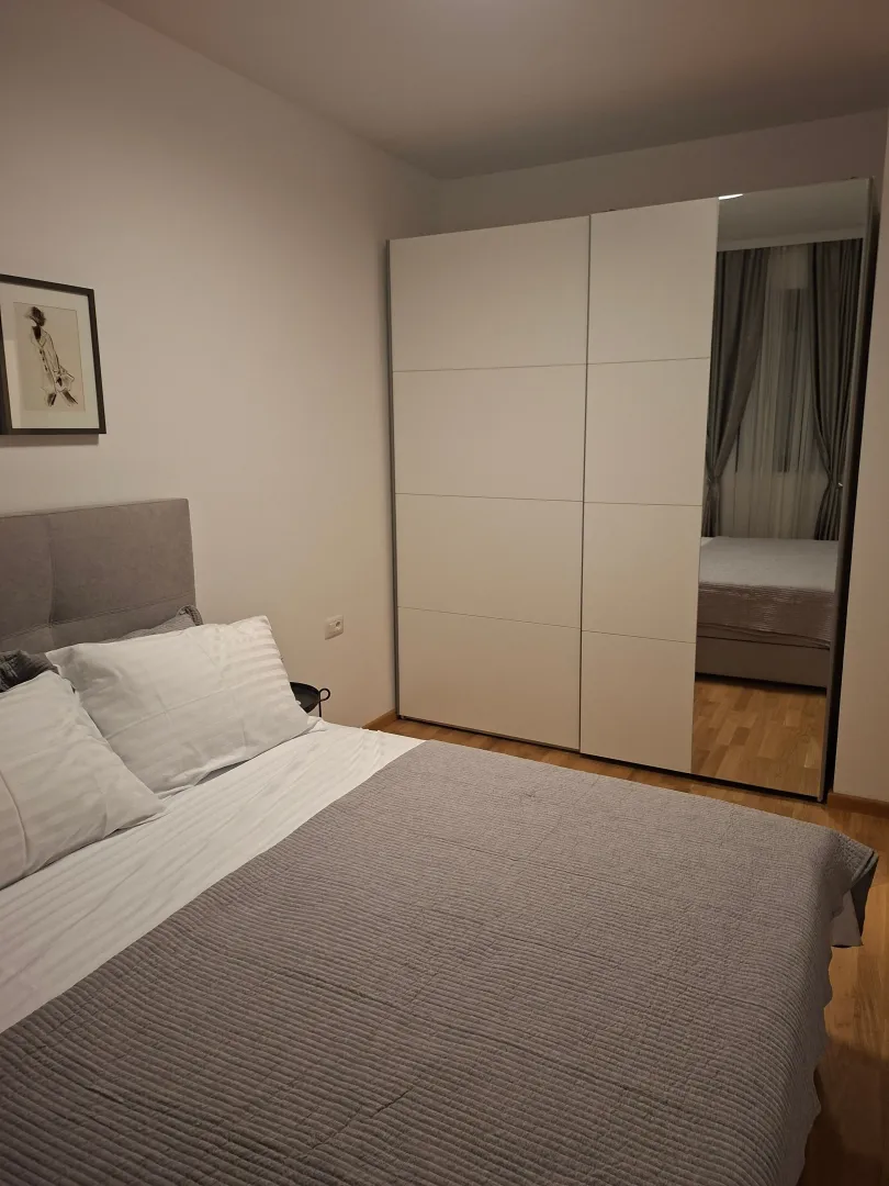 Furnished bedroom with a double bed and a large mirrored wardrobe.