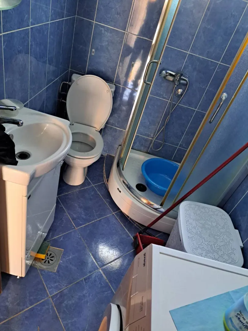 Bathroom with blue tiles, shower cabin, washbasin and toilet.