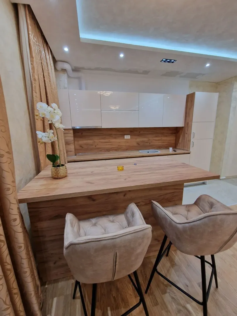 Modern kitchen with wooden elements, a bar counter, and two bar stools.
