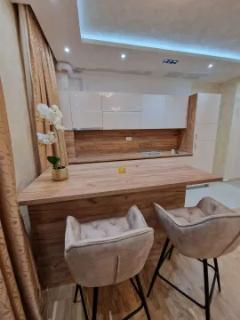 Modern kitchen with wooden elements, a bar counter, and two bar stools. - image 3