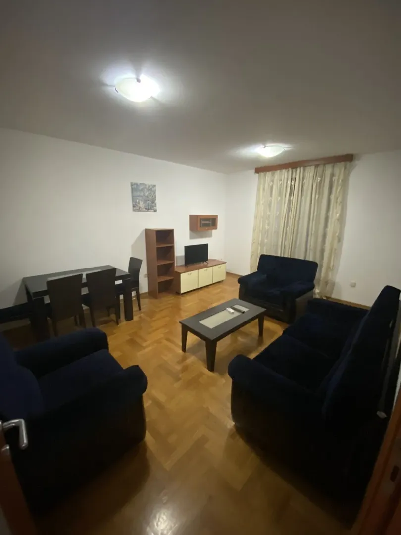 Living room with dark blue sofas and a dining area.