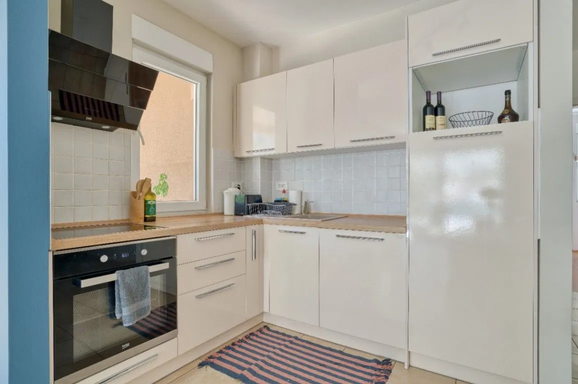 Bright kitchen with white cabinetry and a built-in oven.