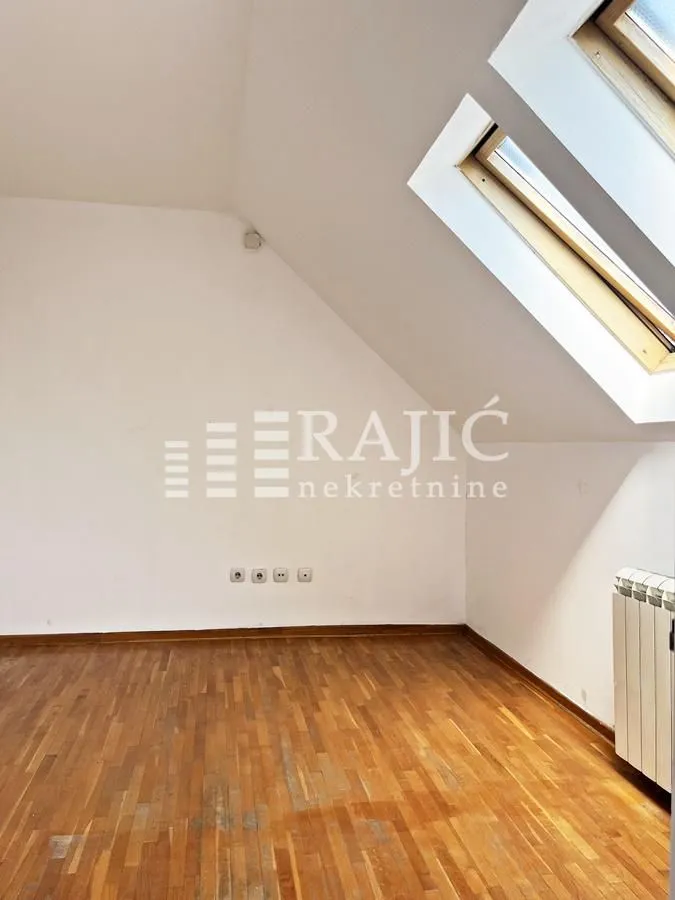 Empty room with parquet flooring and a skylight.