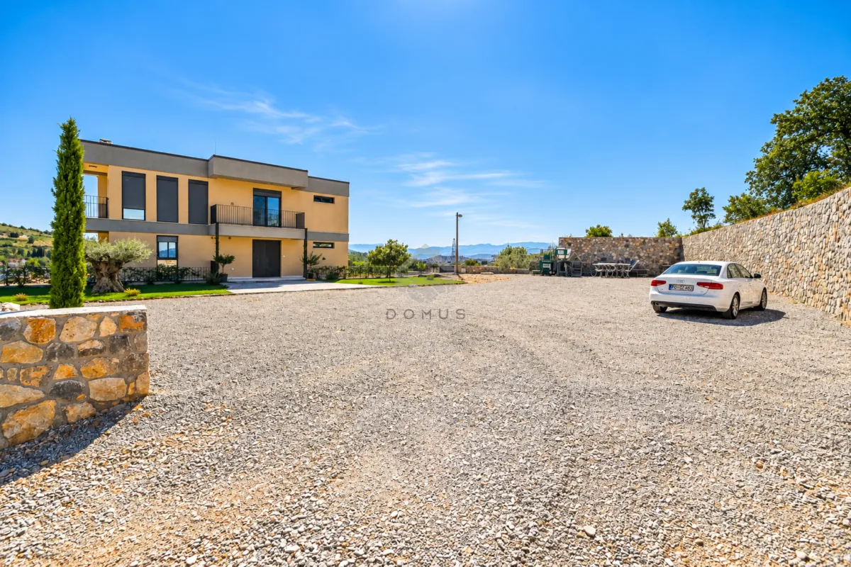Exterior of the house with a courtyard and parking area.