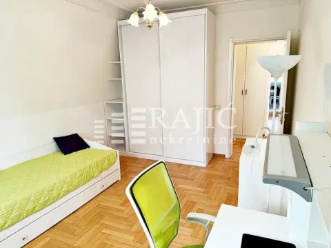 Furnished bedroom with a bed, desk, and white wardrobe. - image 9