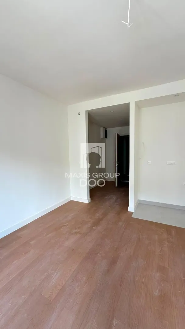 Empty room with wooden flooring and white walls.