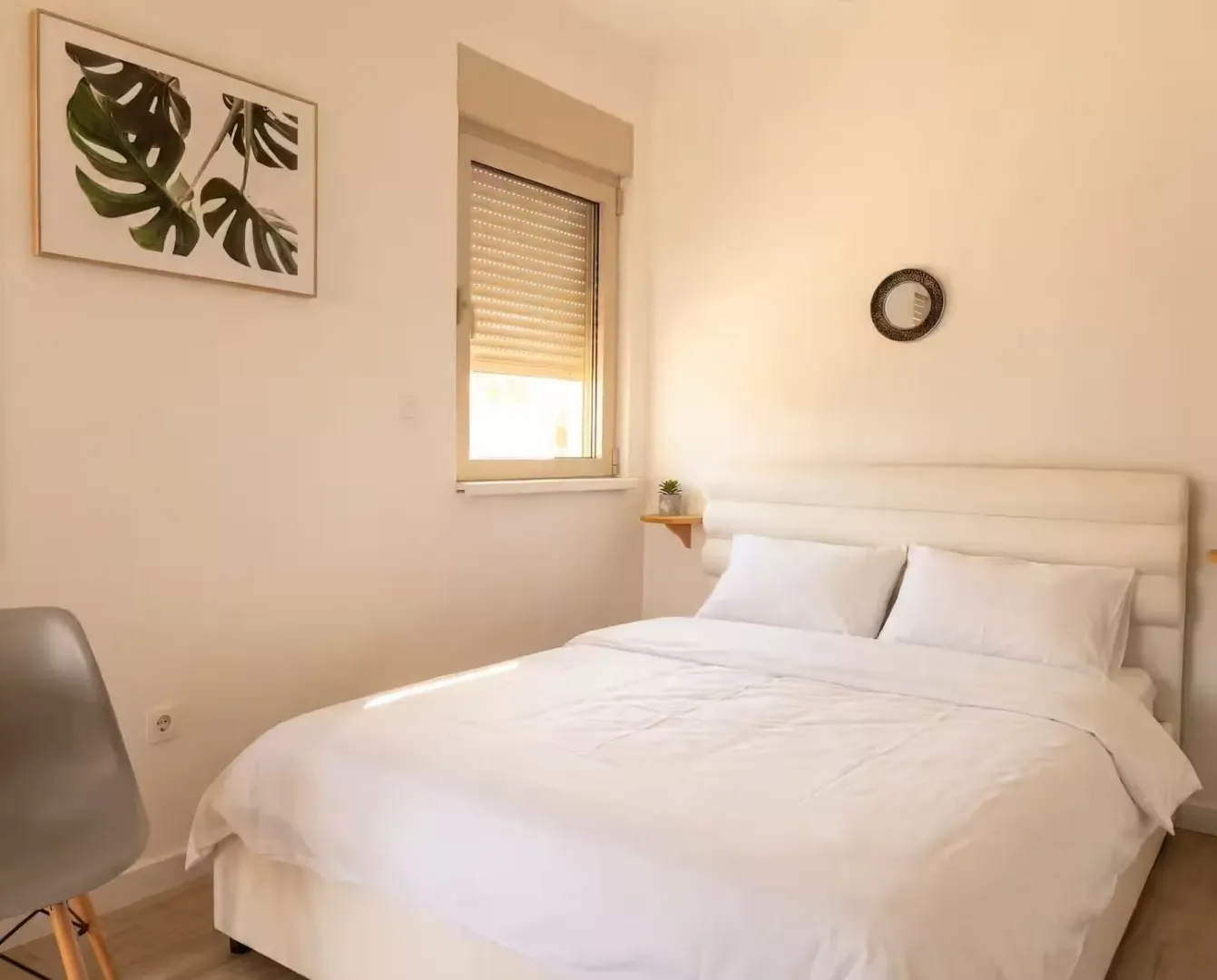 Bright bedroom with a double bed, window, and wall decoration.