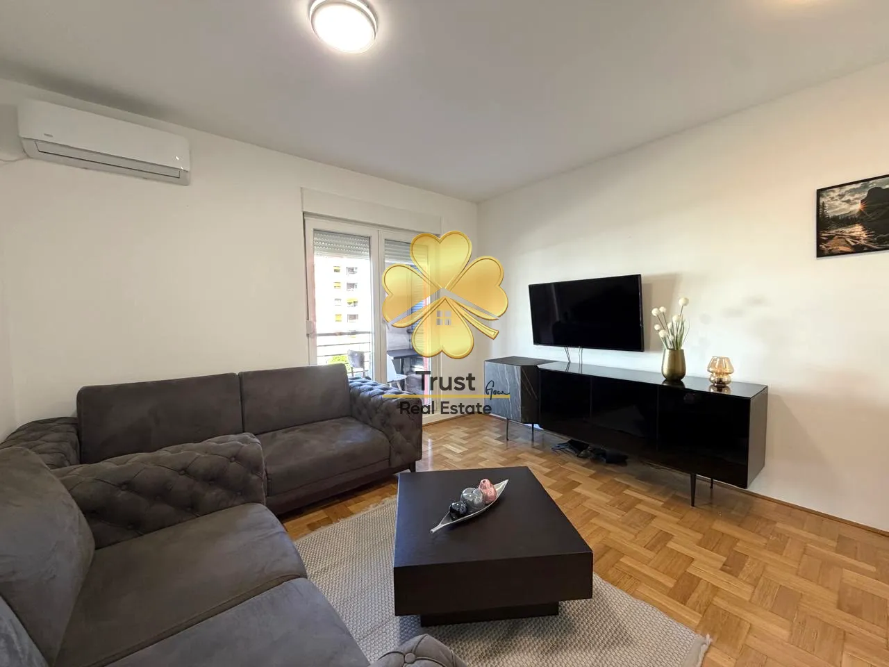 Furnished living room with a sofa, TV cabinet, and balcony access.