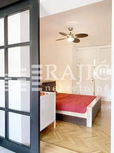 Bedroom with a double bed, crib, and parquet flooring.