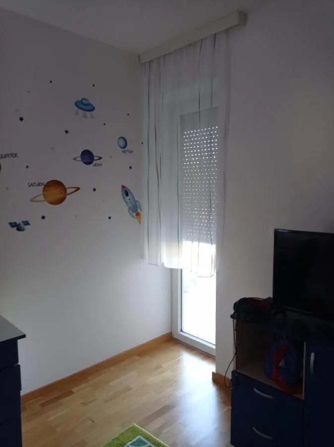 Dečja soba sa zidnim nalepnicama sa motivom svemira i izlazom na terasu.