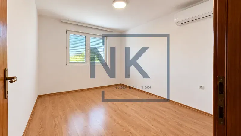 Empty room with laminate flooring, white walls, and an air conditioner.