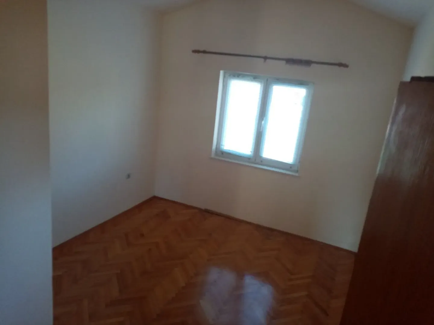 An empty room featuring parquet flooring and a single window.