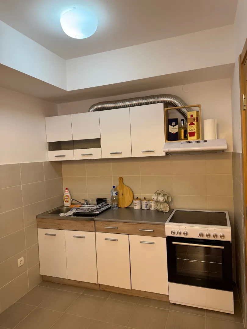 Small kitchen with white cabinets, sink, and electric stove.