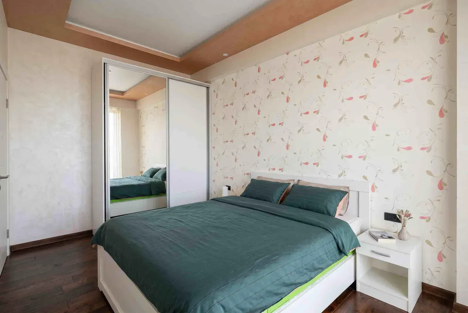 Furnished bedroom with a double bed, mirrored wardrobe, and a nightstand.