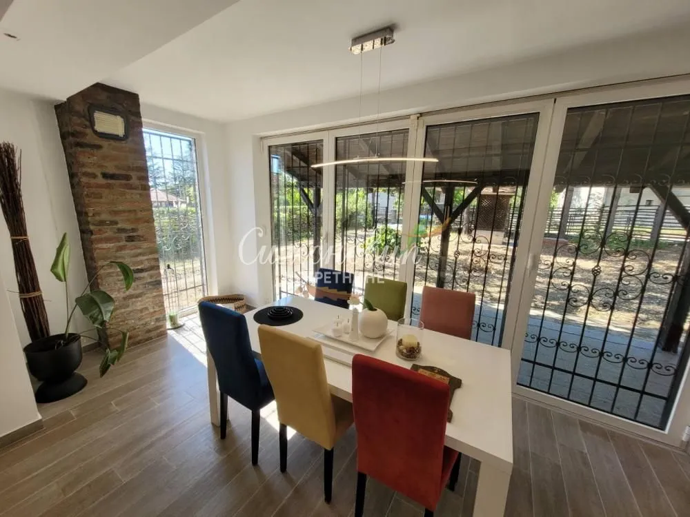 Dining area with a table and colorful chairs next to large glass doors.