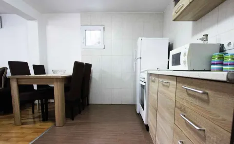 Kuhinja sa drvenim elementima i trpezarijskim stolom sa stolicama. - image 10