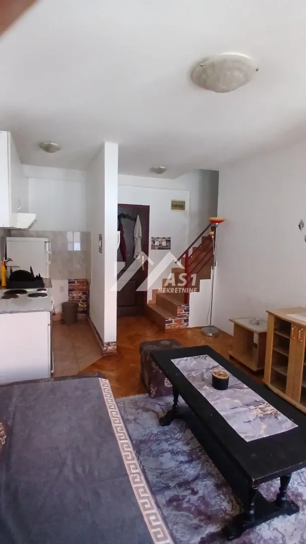 Dnevna soba sa kuhinjom i stepeništem koje vodi na sprat.