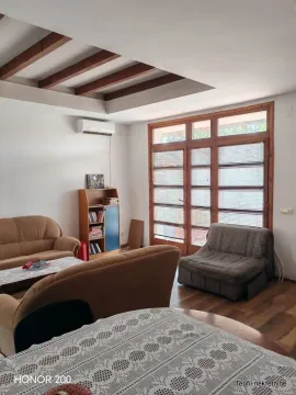 Dnevna soba sa garniturom za sedenje i drvenim gredama na plafonu. - image 4