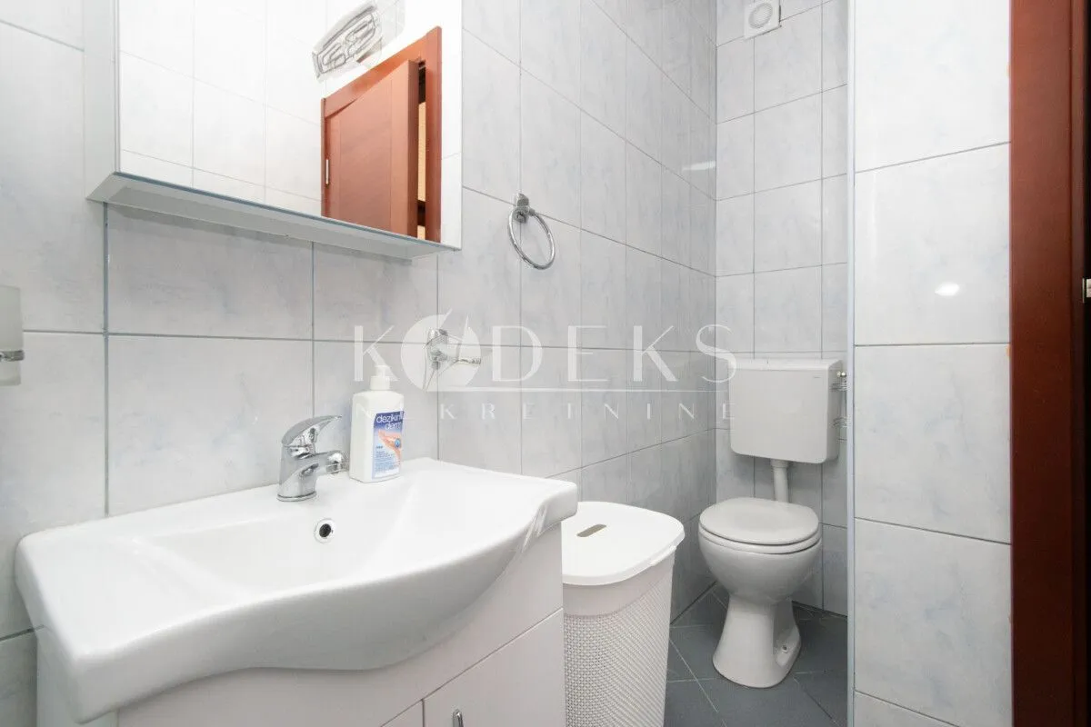 Kupatilo opremljeno umivaonikom, WC šoljom i ormarićem sa ogledalom.