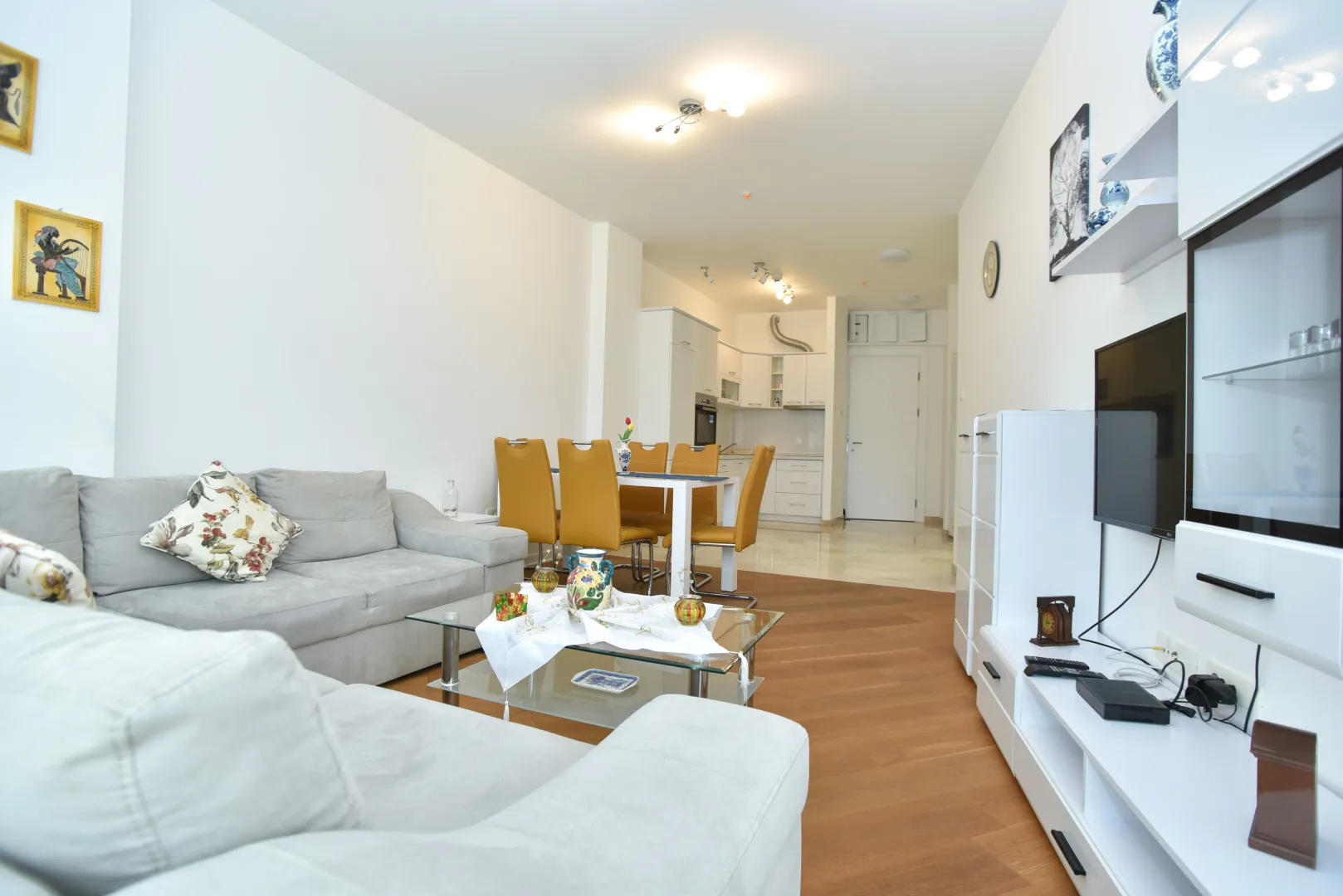Spacious living room with a sofa set, dining area, and kitchen in the background.