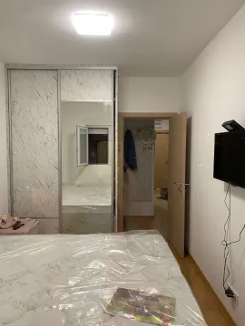 Furnished bedroom with a double bed, large wardrobe, and television. - image 3