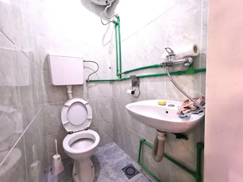 Smaller bathroom with a toilet, washbasin, and visible plumbing. - image 4