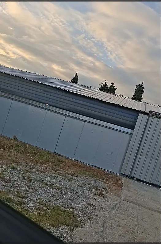 Exterior of a metal auxiliary building under a cloudy sky.