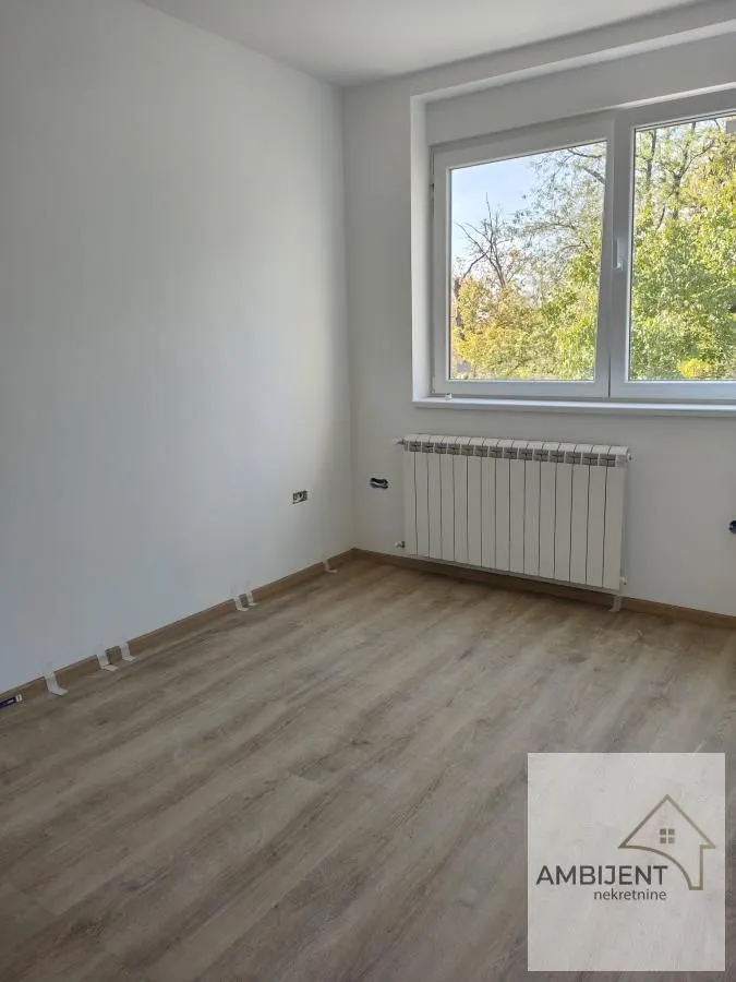 Empty room with laminate flooring, white walls, and a window.