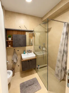 Bathroom equipped with a washbasin, toilet, and a glass shower cabin with a curtain. - image 10