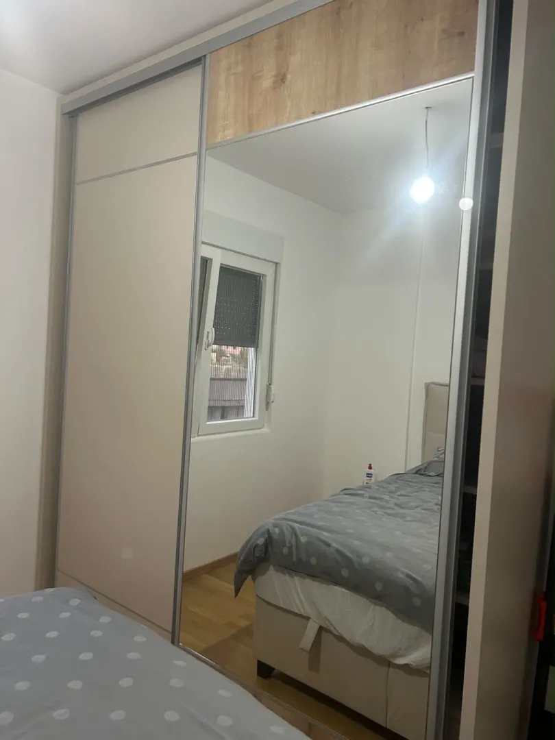 A bedroom with a large mirrored wardrobe and a bed.