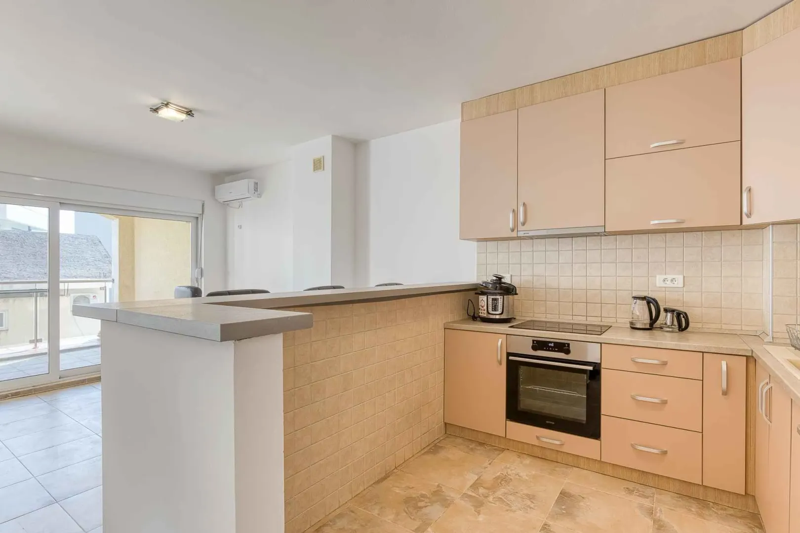 Kitchen with a breakfast bar, fitted appliances, and access to the terrace.