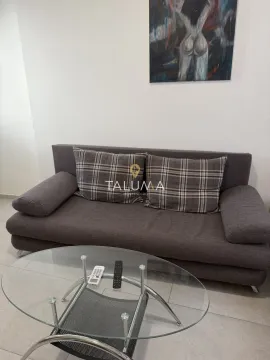 Dnevna soba sa sivom sofom i staklenim stočićem. - image 3