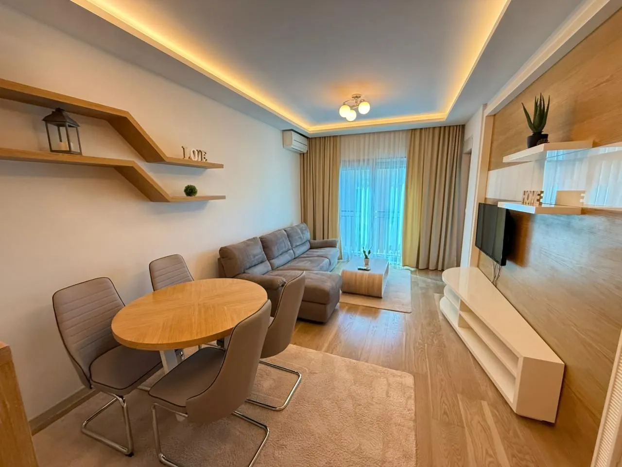 Living room with a sofa, dining table, and TV unit.