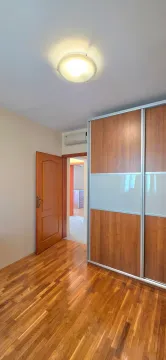 Spavaća soba sa velikim drvenim garderoberom, drvenim podom i otvorenim vrata. - image 14