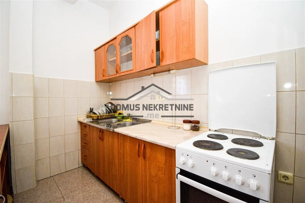 Small kitchen with wooden cabinetry and a white stove.