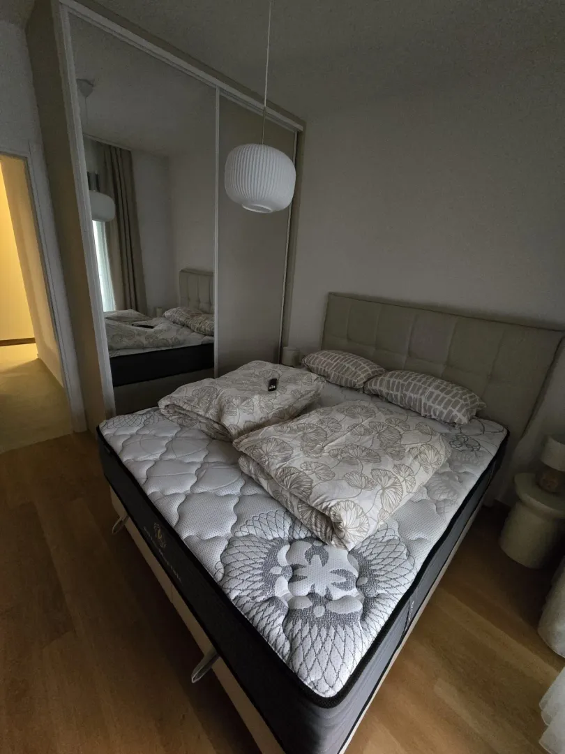 Bedroom with a double bed, mirrored wardrobe, and a pendant lamp.
