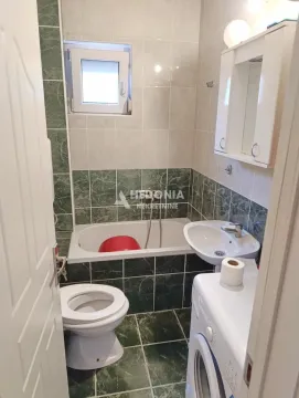 Small bathroom with a bathtub, washbasin, toilet, and washing machine. - image 3