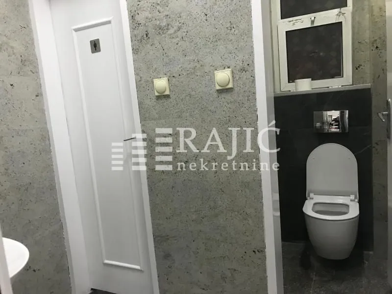Modern bathroom with a toilet and gray wall tiles.