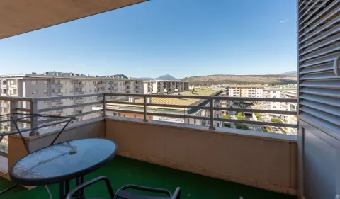 Namješten balkon sa stolom, stolicama i pogledom na okolne zgrade i brda. - image 14