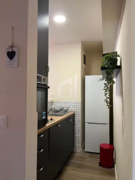 View of a narrow kitchen with dark cabinets and a white refrigerator. - image 3