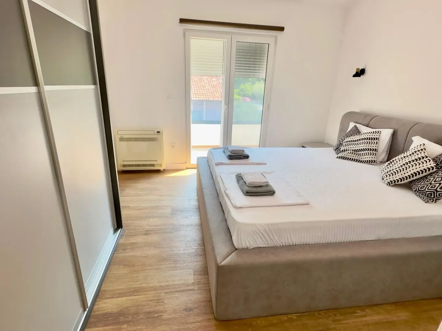 Bright bedroom with a double bed, wardrobe, and terrace access.
