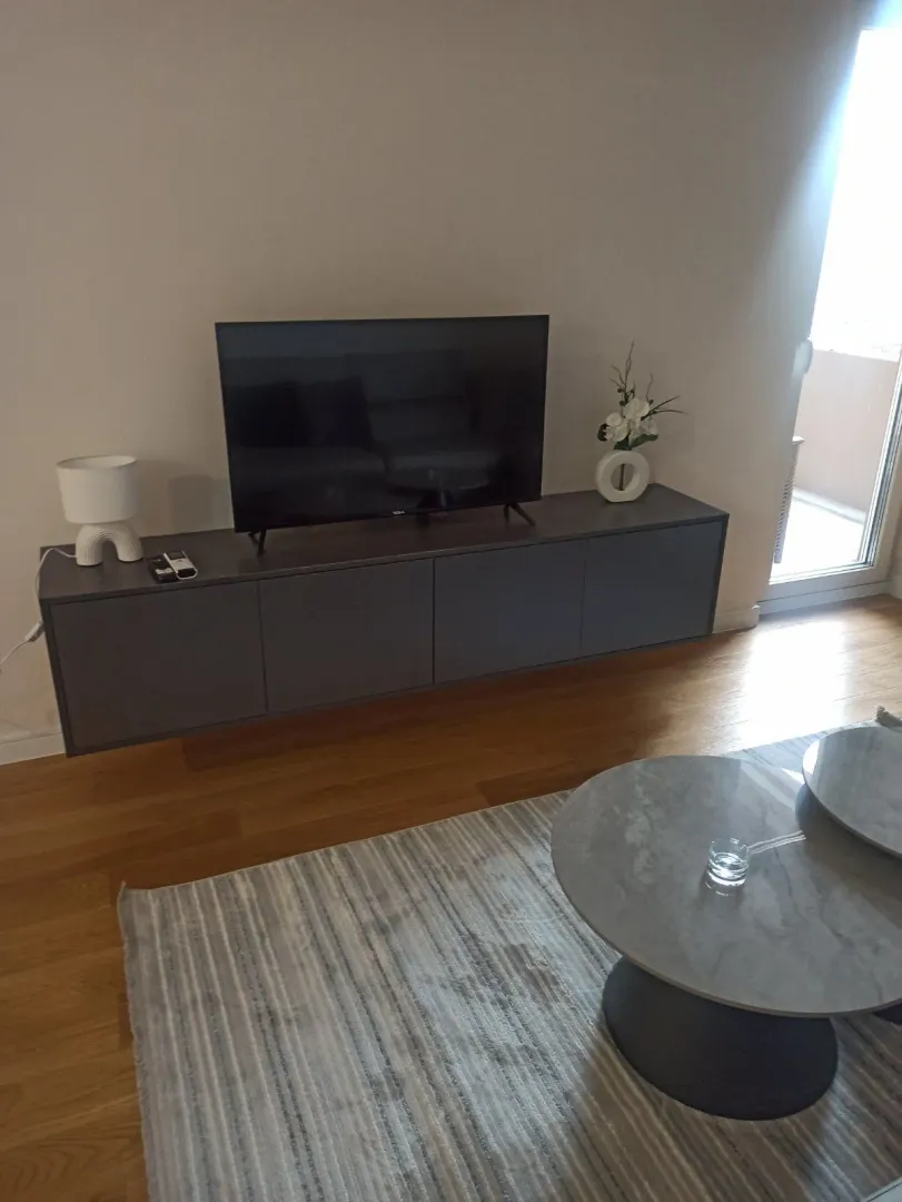 Dio dnevne sobe sa TV komodom i okruglim klub stolovima.